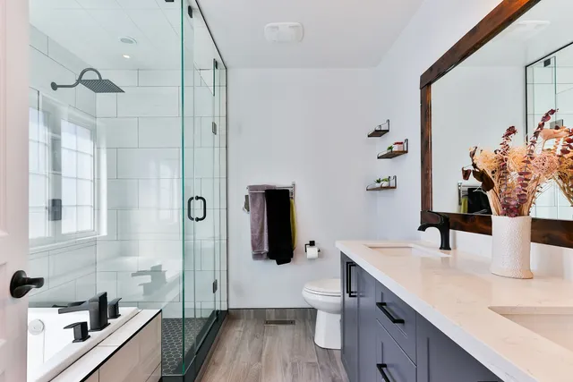 Walk-in tiled shower with glass door and white wall tile